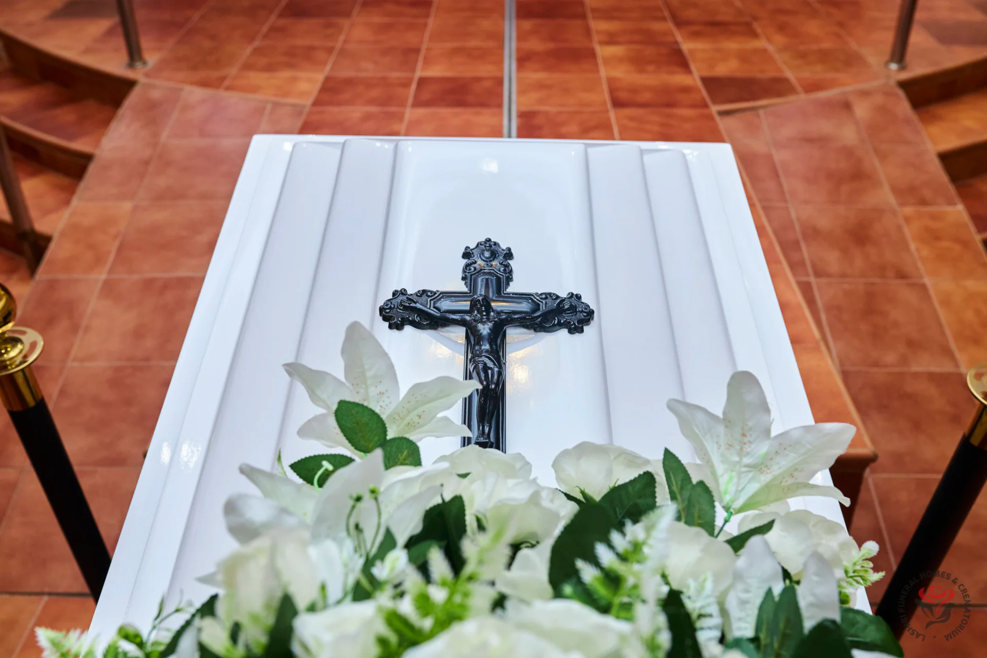 A casket with floral tributes and a crucifix
